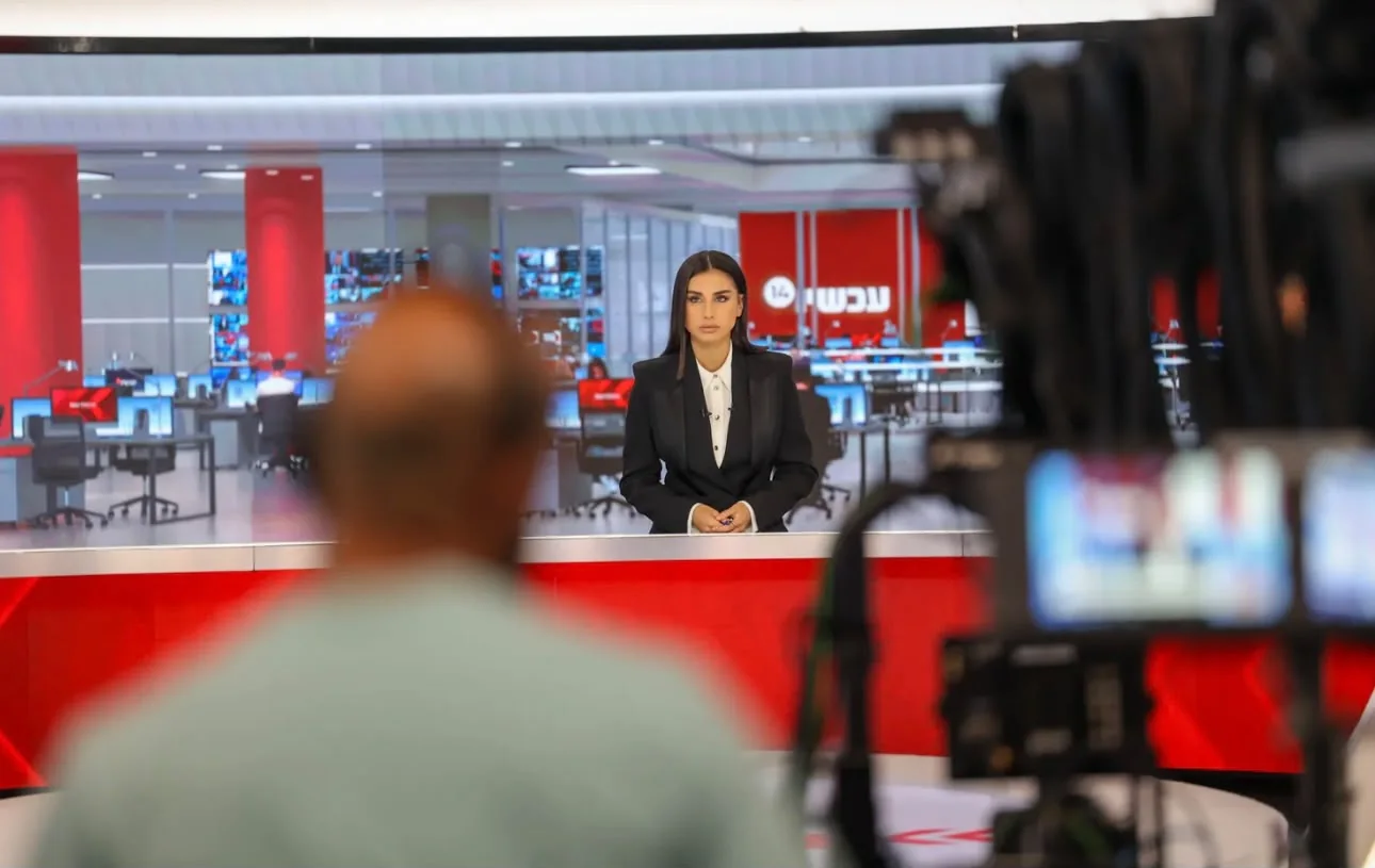 Maggie Tabibi at the news desk, seen through studio cameras